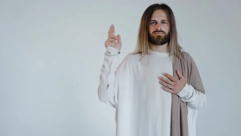 Jesus with a raised hand looks into the camera on a white background. Studio. Vídeo Stock 160494533