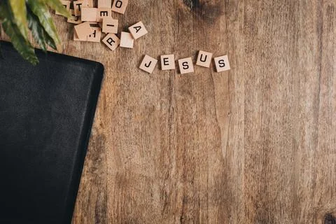 Jesus spelled in block letters on a wooden table with a bible and a plant Stock Photos
