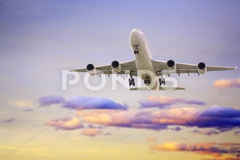 Jet aeroplane landing from sunset sky purple yellow horizontal Stock Photos