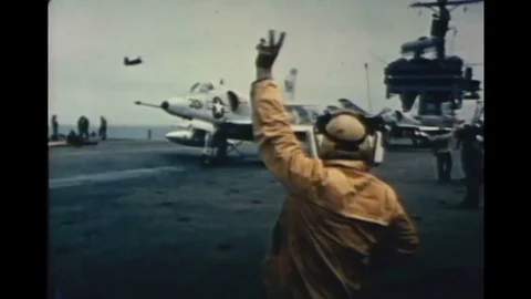 Jet aircraft fly and takeoff from an aircraft carrier to exciting 1970s jazz Stock Footage 110729565