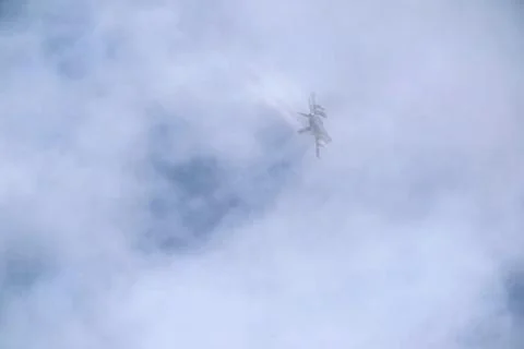 Jet aircraft flying through clouds leaving a vapor trail. Stock Photos