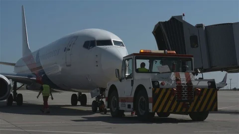 Jet bridge is removed from plane while pushback tug waits connected to the plane Stock Footage 94005203