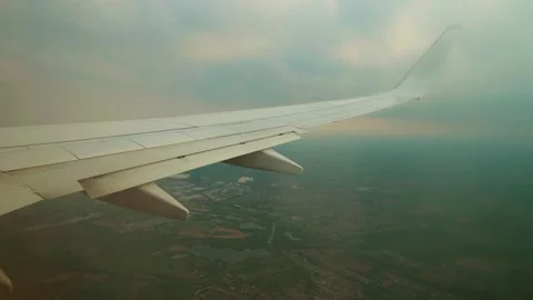 Jet descending under clouds above suburban area. Airplane landing through Stock Footage 329771223