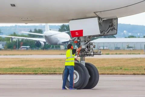 Jet engine aviation technician posing next to a commercial aircraft on the ru Fotos Stock