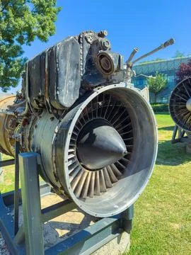 A jet engine is placed on a metal stand in an outdoor museum. The grass is gr Foto stock