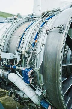 A jet engine stands on display at an airfield. The image captures various par Stock Photos