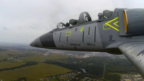 Jet fighter flies over river, green fields and village against a dark cloudy sky Stock Footage 118676989
