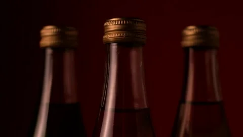 A jet of flame passes by three glass bottles in the dark on a red background Stock Footage 149602360