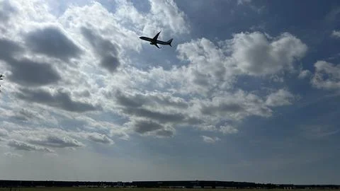 Jet flying above dramatic cloudscape over airport horizon with wide open sky Fotos Stock
