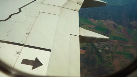 Jet flying over patchwork of farmland and small village, view from window Видео 331160281