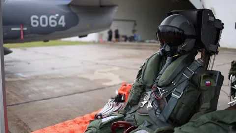 Jet pilot mannequin in full flight gear sits beside military aircraft on wet run Stock Footage 311661944