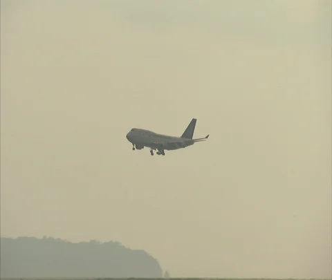 Jet plane ascending over ocean, tilt down to surf rolling up on shore. Stock Footage 86747079