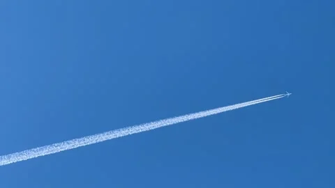 A jet plane creates a white trail across the blue sky, forming a striking geo Video stock 301865515