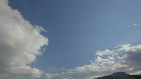Jet plane flying across the  sky, leaving white trail between big clouds. Stock Footage 8562087