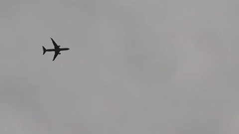 Jet plane flying high in overcast sky Stockbeeldmateriaal 310406842