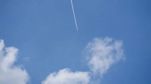 Jet plane flying through the clouds on a bright blue sky Stock Footage 134857684