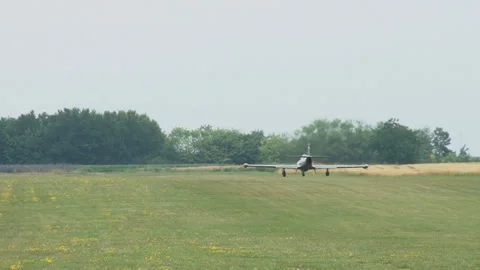 A jet plane rolls on the grass runway of a small city airport. Video stock 134577353