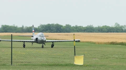 A jet plane rolls on the grass runway of a small city airport. Video stock 134579429