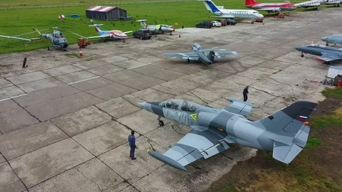 Jet plane stands against many aircraft and helicopters on a cloudy day. Top view Stock Footage 118676002