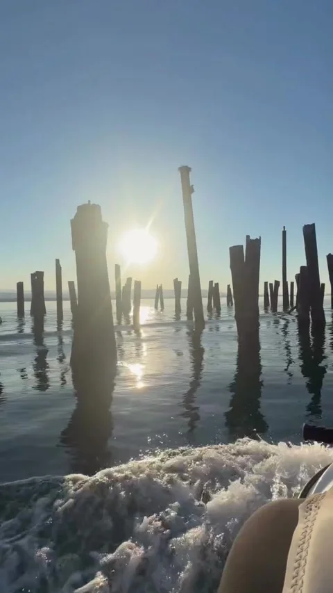 Jet Ski Riding Past Old Wooden Pilings at Golden Hour Sunset Stock Footage 339765040