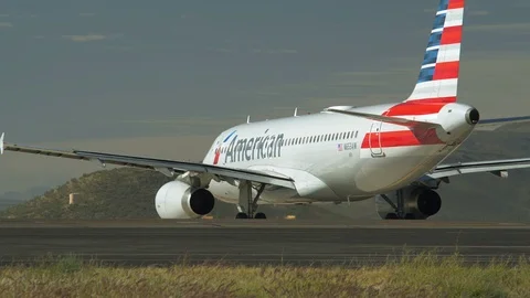 A jet waits to takeoff while another lands at an airport Stock Footage 98615799
