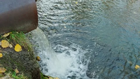 A jet of water from a downpipe falling into a natural stream. Video stock 265387796