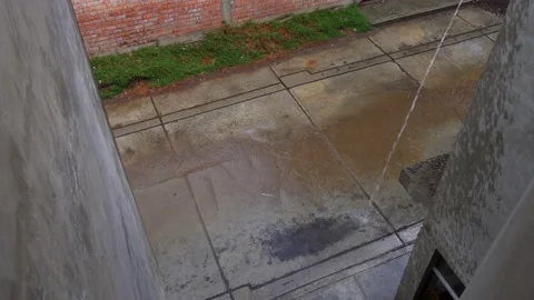 Jet of water falling from a pipe in heavy rain from the roof on the roof of a Vidéo 164621388