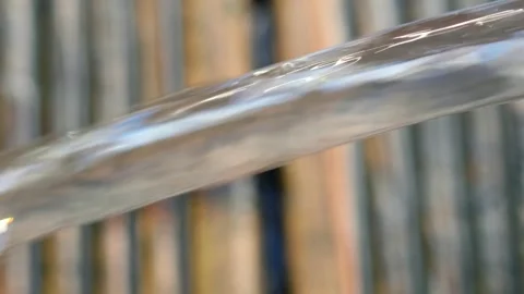 Jet of water flows out of a blue swimming pool onto wooden decking Stock Footage 250006567