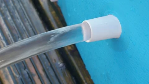 Jet of water flows out of a blue swimming pool onto wooden decking Stock Footage 250006570
