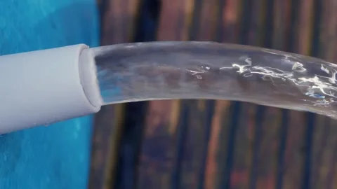 Jet of water flows out of a blue swimming pool onto wooden decking Stock Footage 250006617