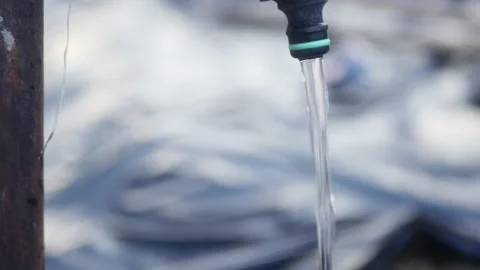 Jet of water from a rusty pipe flowing down from a plastic faucet Vidéo 171051279