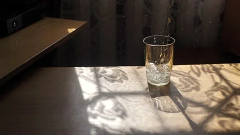 A jet of water in slow motion falls into a glass, creating air bubbles after Stock Footage 202199906