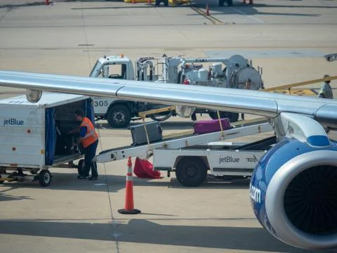 JetBlue baggage handler loading luggage into an airliner at Reagan International Foto stock