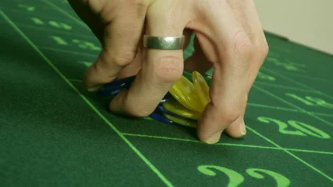 Jetons are put down by hand on the green Roulette table Video stock 219643973