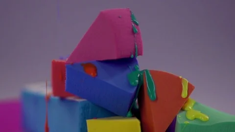 Jets of multi-colored nail polish drip onto the make-up sponge. Video stock 77512118