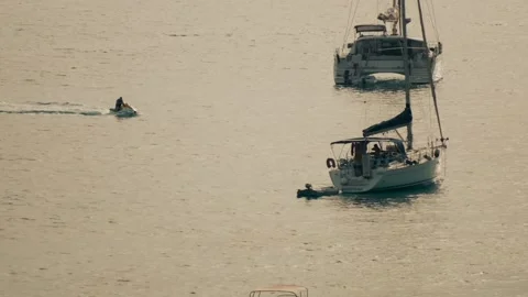Jetski drives between two sailboats Stock Footage 229194464