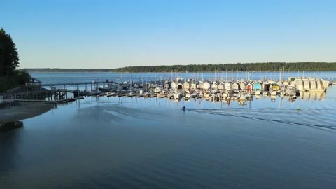Jetski pulling into dock pier, sunset, sailboats, calm water, green trees Stock Footage 155725147