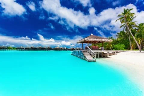 Jetty and palm trees with steps into tropical blue lagoon Stock Photos