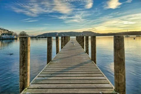 A jetty on a calm Windermere at sunset. Stock Photos