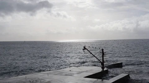Jetty with red crane in the rough sea three quarter view Stock Footage 101910223