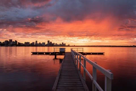 Jetty at sunrise with dramatic storm clouds and still water Stock Photos