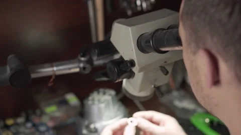 Jeweler examines the ring under a microscope. Blured background. Stock Footage 153549310