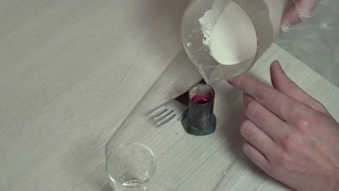 A jeweler pours plaster solution into a mold with a wax model. Stock Footage 147414905