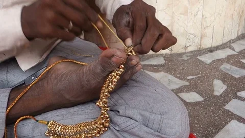 A jeweler works on gold using his feet and hands in India Stock Footage 83655448