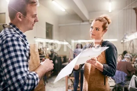 Jewelers discussing blueprint in workshop Stock Photos