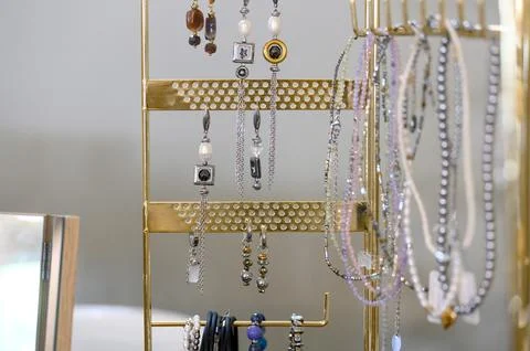 Jewelry display rack featuring various earrings and necklaces in bright setti Stock Photos