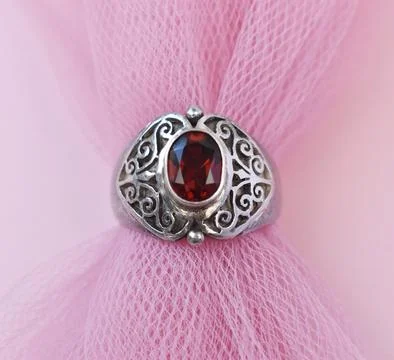 Jewelry silver ring with red ruby on pink fabric background. 스톡 사진