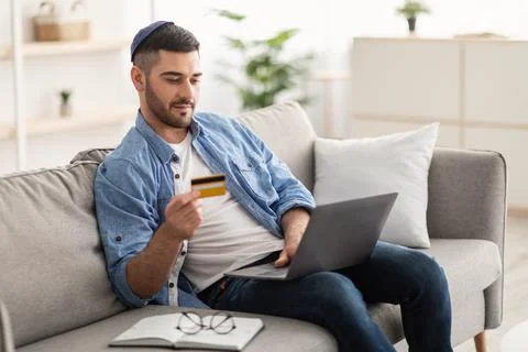 Jewish guy using pc and credit card at home Stock Photos