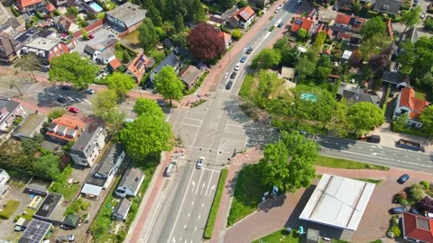 Jib down of busy intersection with cars and cyclists on sunny day Stock Footage 241765142