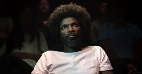 Jib down shot of a man siting in a movie theatre watching a movie. Vídeo Stock 83735574